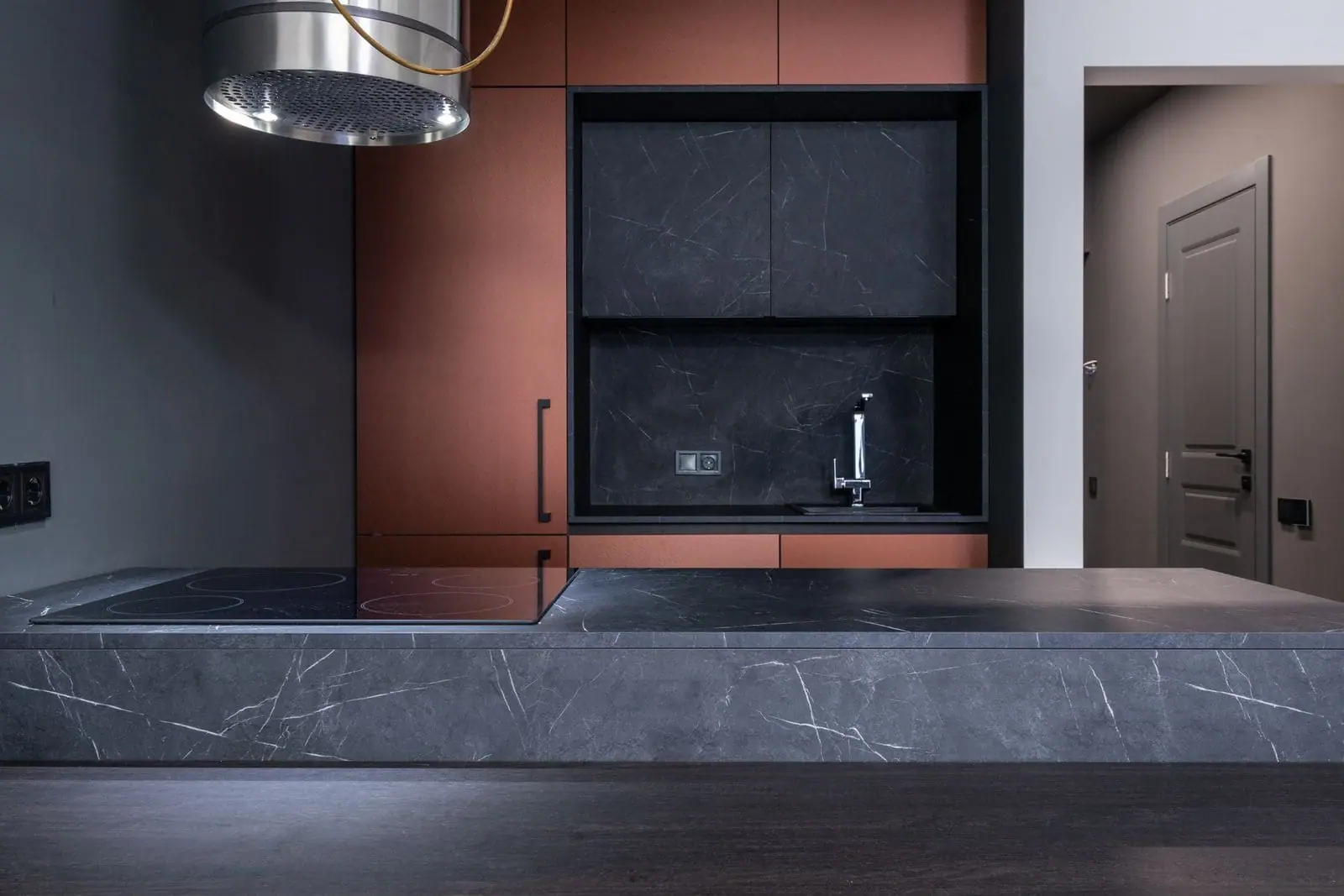 Kitchen with terracotta cabinets and a dark stone worktop